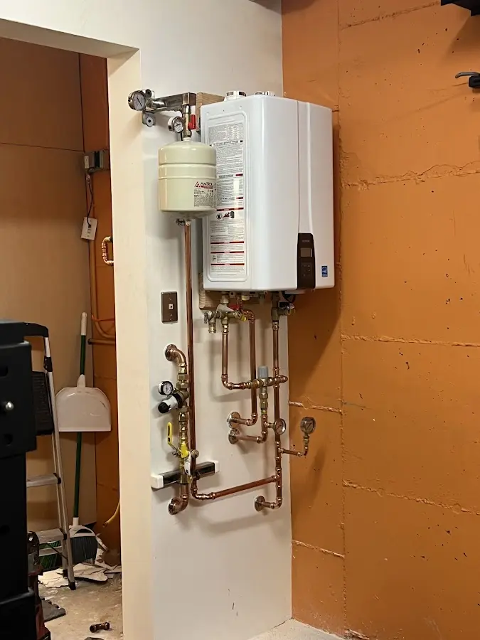 Plumbing technician inspecting water heater connections in Genesee